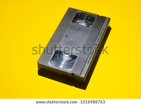 Retro videocassette from 80s on a yellow background. Obsolete media technologies.