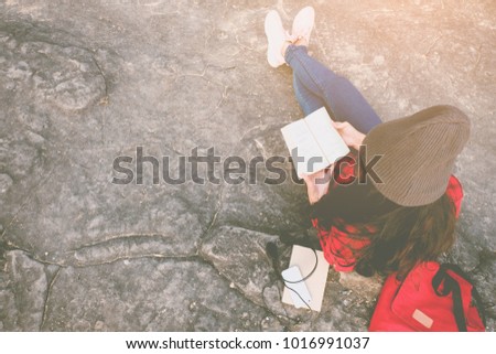 Relaxing moments, Young woman reading a book by the lake. Solo relaxation, color of Hipster Tone. Top view