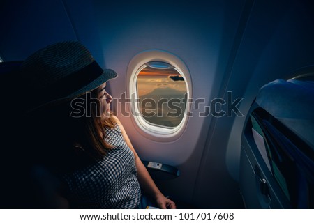 Young asian woman traveler looking view at window in airplane with happiness and relaxing Royalty-Free Stock Photo #1017017608