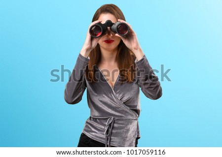 Beautiful young girl with binoculars on colorful background