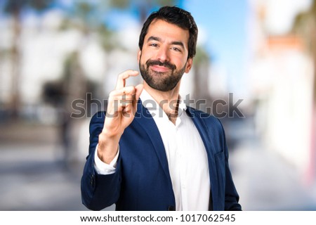 Handsome man making tiny sign on unfocused background