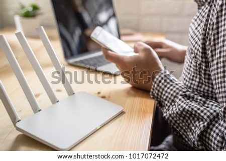 closeup of a wireless router and a man using smartphone on living room at home ofiice