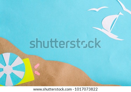 Summer background with sailboat sailing in the sea, beach umbrella and mat. Paper cut.