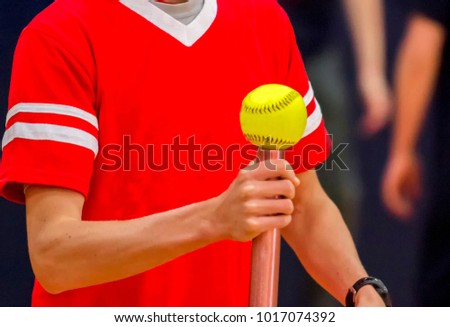 A high school athlete is balancing a softball on a baton for a fun relay race.