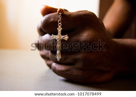 African man's hand holding Cross in prayer  Royalty-Free Stock Photo #1017078499