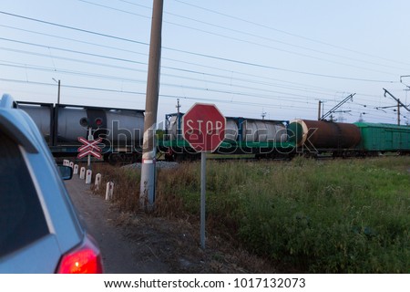 The car stopped at a closed railway crossing. Freight train at crossing gate