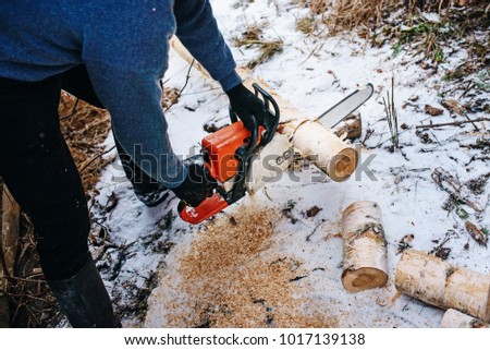 Process of sawing log by chainsaw in the winter .