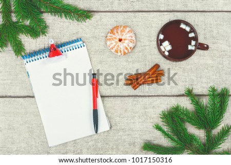 Christmas letter. Cup of hot coffee with cinnamon and marshmallow, tangerine, fir branches and pine cone on wooden white background with decorations. New year's greetings. Xmas to-do list and wishes.