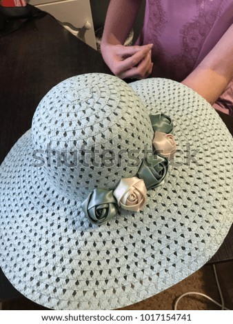 The girl decorates the sun hat with flowers made of silk.