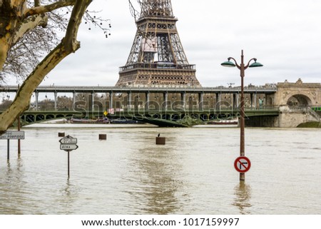 The swollen Seine during the winter flooding episode of January 2018, with half immersed road signs and street lights in the foreground and the Eiffel tower and Bir-Hakeim bridge in the background.