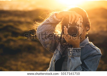 Beautiful woman taking picture outdoors with a analog camera