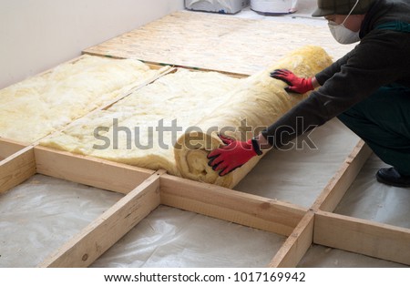 Work composed of mineral wool insulation in the floor, floor heating insulation, warm house, eco-friendly insulation, a builder at work Royalty-Free Stock Photo #1017169942