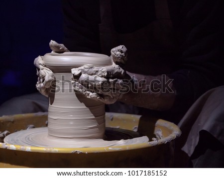 Close-up of human hands making clay dish on a pottery wheel.