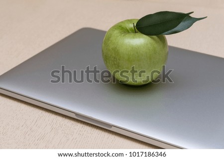 The green fresh Apple lies on the laptop.