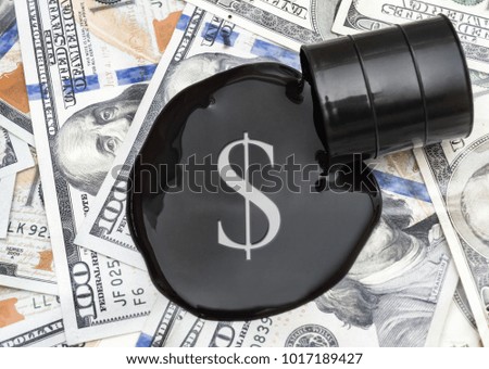 Sign of dollar on crude oil spilled from barrel on the dollars background. Top view.