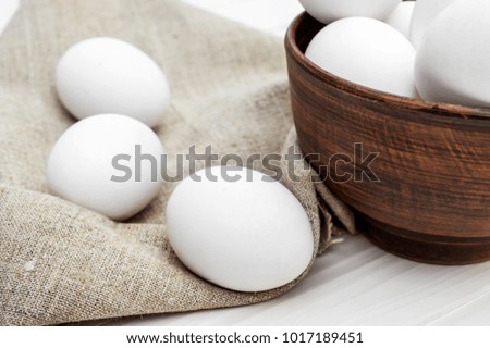 Bowl with eggs and eggs on the sackcloth on the table.