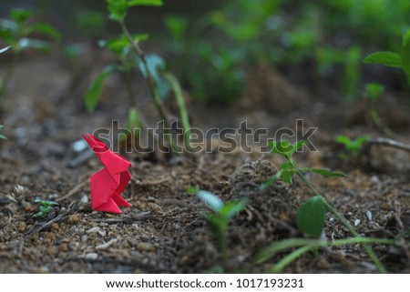Red origami rabbit on a playground with copy space. Selective focus shot.