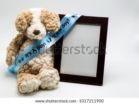 plush toy bear with blue satin ribbon saying 'Its A Boy" next to empty picture frame to customize