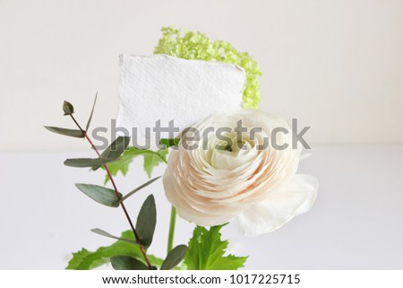 Wedding or birthday mock-up scene with floral bouquet of Persian buttercup, Ranunculus flower and eucalyptus leaves with blank paper greeting card. Feminine styled stock image.
