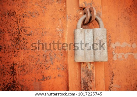 Padlock on a rusty brown metal door. Processed for vintage tone effect. Rusted iron orange plate door with handle and lock