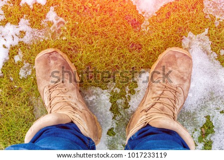 photo background of men's boots close-ups stand on snow and green grass