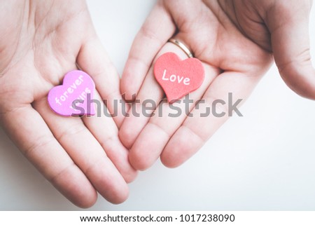 Valentine day concept. Red decorative heart with love inscription and purple heart with inscription forever yours in female hands. Toned.