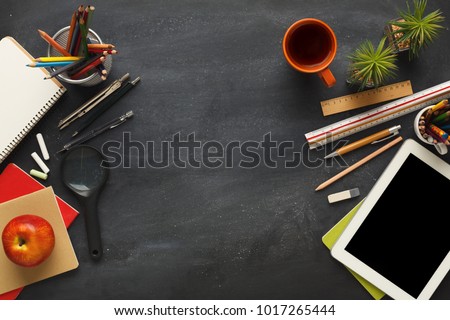 Top view on school educational supplies. Desktop with digital tablet, ruler, pencils, pens, notebooks, magnifying glass and cup of coffee. Studying and researching background, copy space