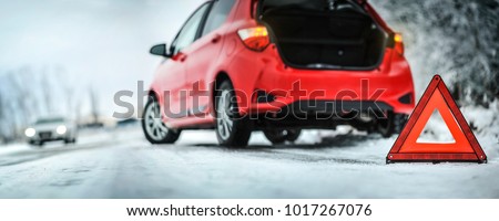 Car red triangle in winter. Emergency sign. Broken car on highway. Warning triangle on snow after car breakdown.
