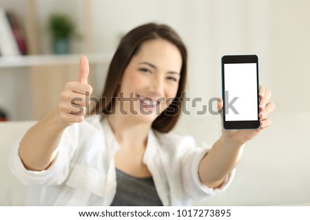 Front view portrait of a happy female showing a blank smart phone screen at home