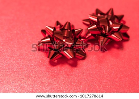 Two red paper gift bows on red background. Holiday season, birthday, valentines or gift wrapping concept