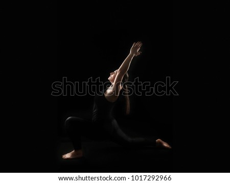 Silhouette of plus size woman doing yoga,isolated over dark studio background