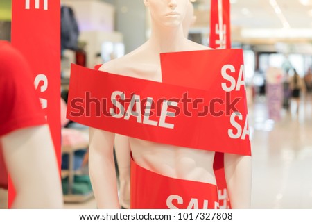 Sale signs in a clothing store hanging on a mannequins with sale tag in a clothing store.