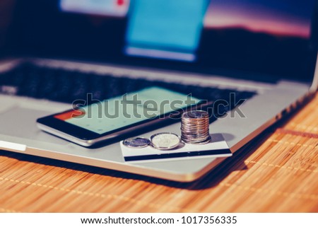 A stack of coins on credit cards next to the smartphone with a calculator app on the background of a notebook with the personal Cabinet of the Internet Bank. Buy goodsby credit card. . Toned photo