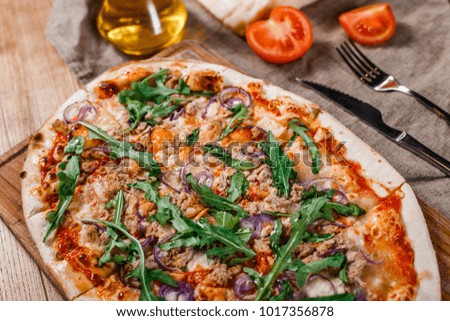 Pizza with chicken, arugula, cheese and onions on wooden rustic table