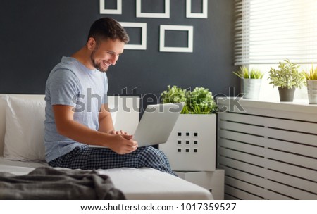 happy young man with laptop and cup of coffee in  the bed
