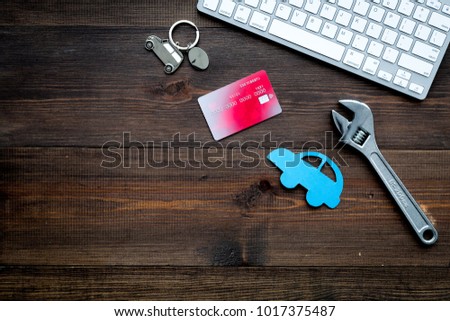 Looking for automobile service online. Cost calculation. Pay for car repair. Car silhouette, wrench, bank card, computer keyborad on dark wooden backgound top view copy space