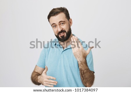 Picture of a handsome middle aged man gesturing while talking, standing near white background. Person is telling to his friends about an amazing story that happened to him during his vacation.