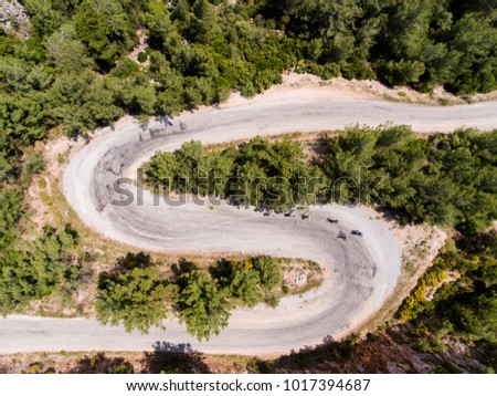 Drone photo of cyclists on an s shaped road, climbing the hill