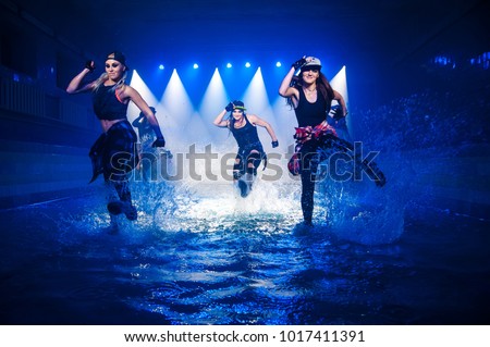 Performance on the water of a dance group against the background of club light. Royalty-Free Stock Photo #1017411391