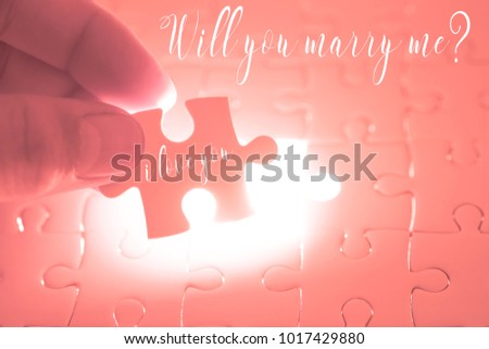 Will you marry me word on pink jigsaw puzzle being holding by the hands of men. Valentines day concept marriage and wedding proposal.