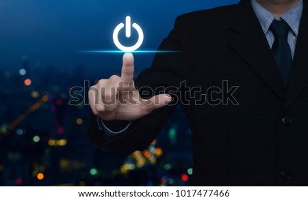 Businessman pressing power button over blur colorful night light city tower, Start up business concept
