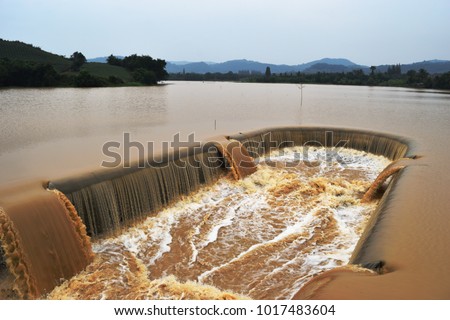 Turbid water in the dam overflows into the spillway , Dams and irrigation in the rainy season, Thailand Royalty-Free Stock Photo #1017483604