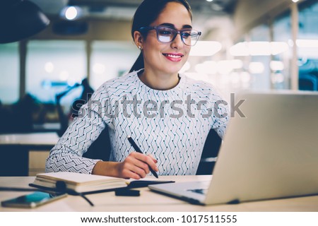 Smart young woman satisfied with learning language during online courses using netbook, smiling female student doing homework task in college library searching information via laptop computer Royalty-Free Stock Photo #1017511555
