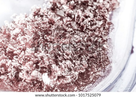 The frozen refrigerated black currant jam in a plastic container. Isolated with path top view macro