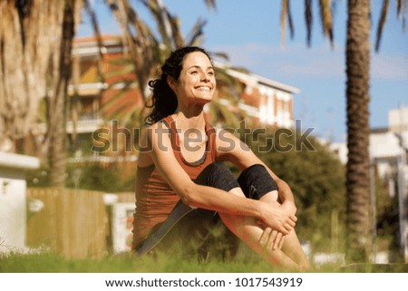 Portrait of young sports woman resting on grass in park