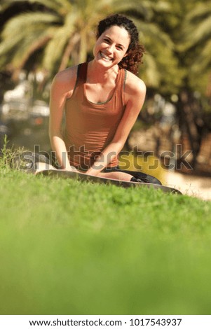 Portrait of happy young yoga woman relaxing outside in park