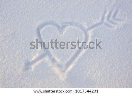 Heart with an arrow drawn on the snow