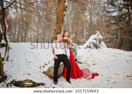 Amazing couple in winter fairytale forest in love. Girl in red beautiful dress. Valentine's Day theme.