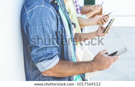 Group of people using smartphones while watching videos outdoor - Friends having fun with technology trends - Youth, tech and friendship concept - Focus on first man hand mobile phone Royalty-Free Stock Photo #1017564112