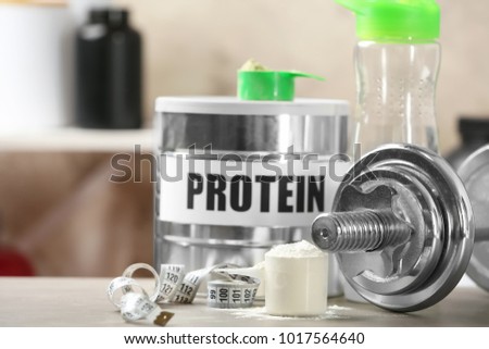 Composition with protein powder and dumbbell on table